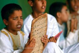 Image du Maroc Professionnelle de  Sous une tente on découvre la méthode traditionnelle de l’enseignement et l’apprentissage du saint coran prodigués aux enfants. Les jeunes récitent les sourates devant le Fkih (instituteur) qui écoute attentivement les versets ainsi récités, Samedi 18 septembre 2006, aux environ de Tan Tan dans un site désertique sur lequel la ville, a toujours accueilli la majorité des tribus et des grandes familles nomades du désert lors d'un grand Moussem, danses chants, course de chameaux et fantasia font partie des festivités. (Photo / Abdeljalil Bounhar)

 